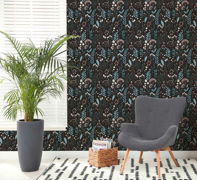 Wohnraum mit Vliestapete mit floralem Blumenmuster, grauer Sessel, Zimmerpflanze und Teppich mit abstraktem Muster.