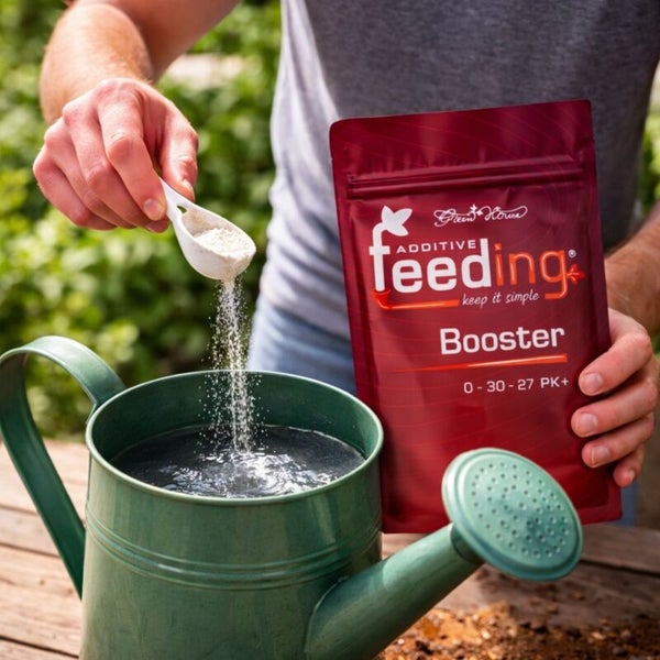 Ein Mann gibt Nährstoffbooster in eine Gießkanne.