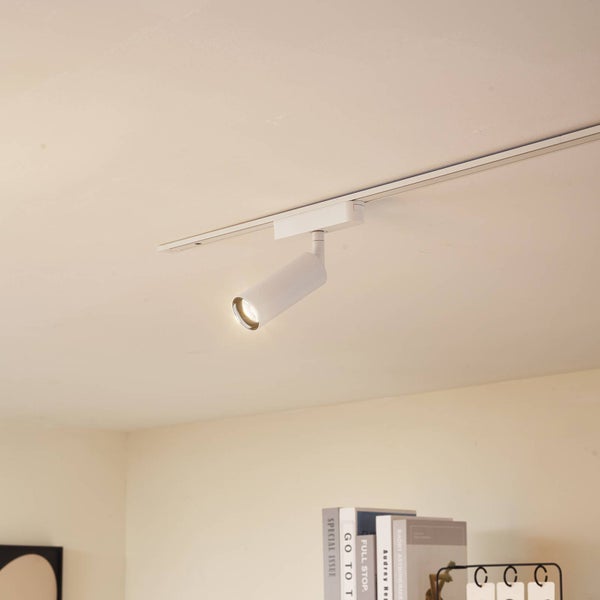 Weißer Schienenstrahler an einer Deckenschiene im Innenraum, eingeschaltet, minimalistisches Design.