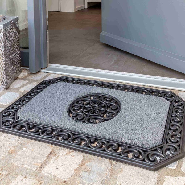 Fußmatte mit Ornamenten und textilem Einsatz vor einer Haustür