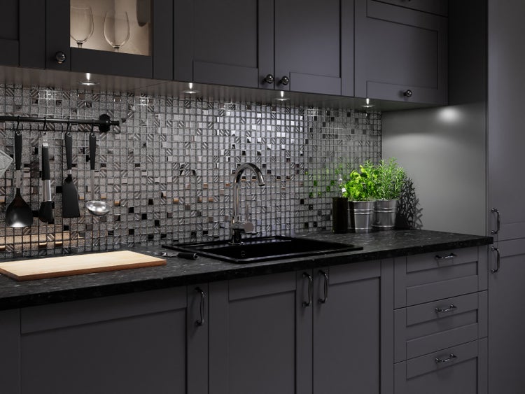 Moderne Küche mit dunklen Fronten, metallischer Mosaik-Rückwand, dunkler Spüle und verchromter Armatur auf einer dunklen Arbeitsplatte.