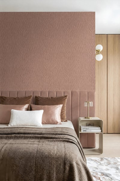Schlafzimmer mit texturierter Mustertapete hinter einem gepolsterten Kopfteil und einem Nachttisch mit einer Tischlampe.