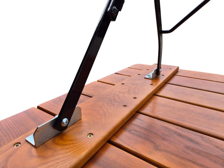 Detailaufnahme der Befestigung eines schwarzen Metallbeins an der Unterseite einer Tischplatte aus Holzlatten.