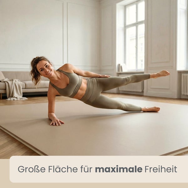 Eine Frau trainiert auf einer großen, flachen Sportmatte in einem hellen, wohnlichen Raum mit Parkettboden und Sofa.