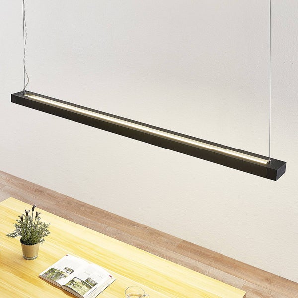 Moderne schwarze lineare LED-Pendelleuchte hängend über einem hellen Holztisch mit einer Pflanze im Topf und einem Buch.