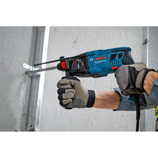 Bosch Professional GBH 2-21 Bohrhammer beim Bohren in eine Betonwand zur Befestigung eines Metallprofils, Person trägt Arbeitshandschuhe.