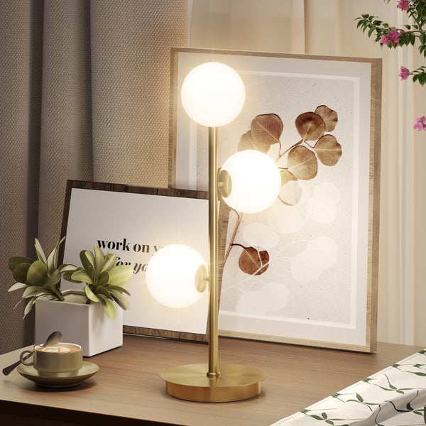 Dekorative Tischleuchte mit drei Glaskugeln auf einem Nachttisch