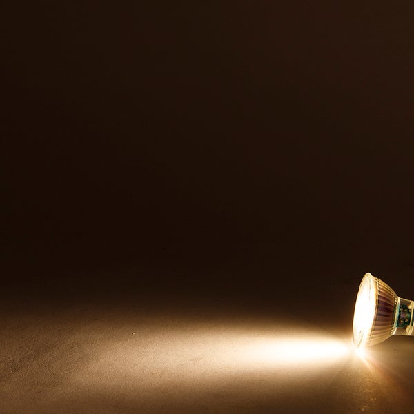 Leuchtendes LED-Leuchtmittel GU10 mit einem warmweißen Lichtstrahl in dunkler Umgebung.