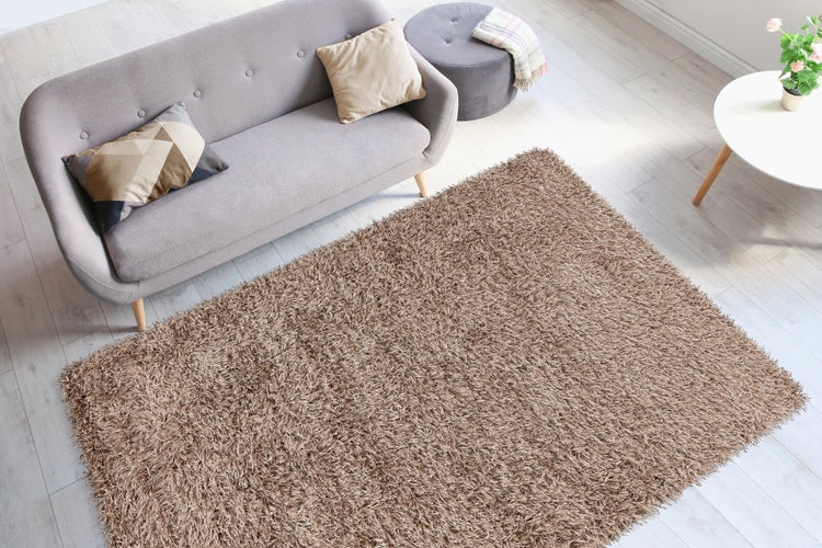 Ein moderner Hochflor Teppich in einem hellen Wohnzimmer mit Sofa und Beistelltisch in Draufsicht.