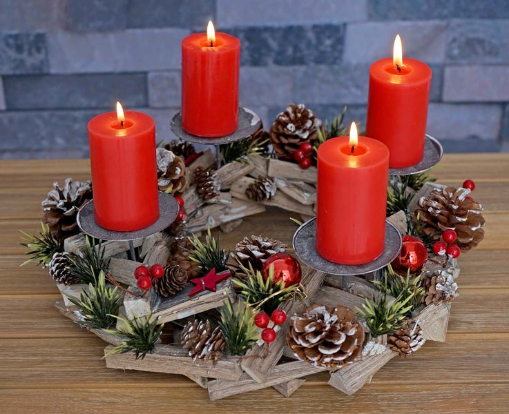Adventskranz mit vier brennenden Kerzen, Tannenzapfen und Dekoration auf einem Holztisch