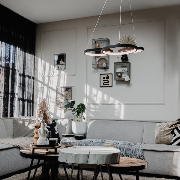 Wohnzimmer mit Couch, Couchtischen und runder Hängeleuchte