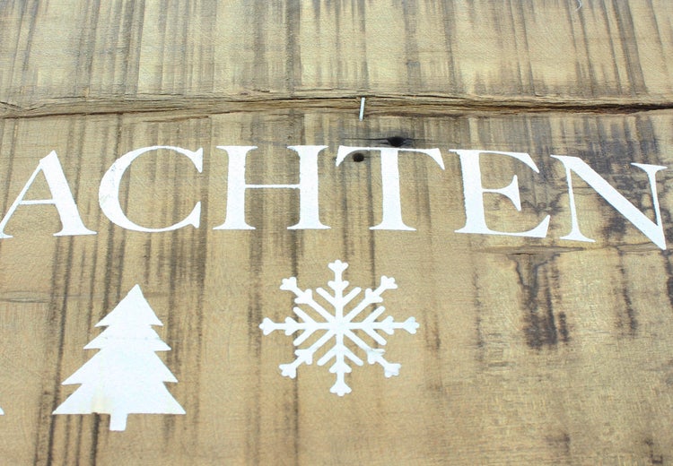 Holzschild mit dem Wort "Weihnachten", einem Baum und einer Schneeflocke