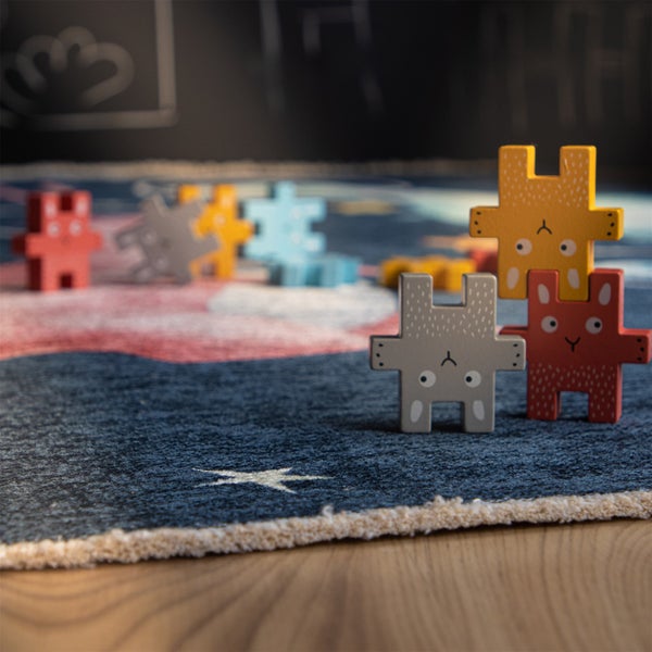 Kinderspielteppich mit Sternenmotiv und Holzfiguren in Hasenform zum Stapeln auf einem Holzboden.