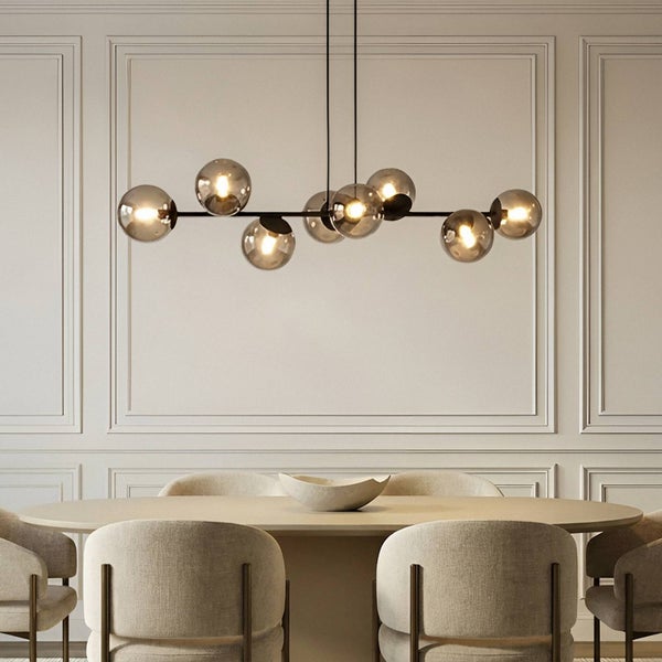 Moderne Pendelleuchte mit runden Glasschirmen über einem Esstisch mit Stühlen