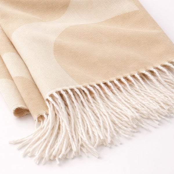 Weiche Wohndecke mit großem Kreismuster und weißen Fransen.