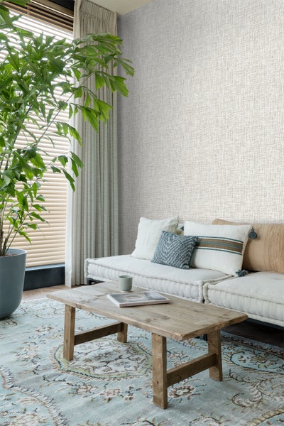 Wohnzimmer mit Sofa, Holztisch, Zimmerpflanze und gemusterter Tapete