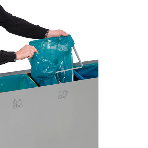Eine Person setzt einen Müllbeutel in ein Mülltrennsystem mit Beutelhalterung und Recycling-Symbolen ein.