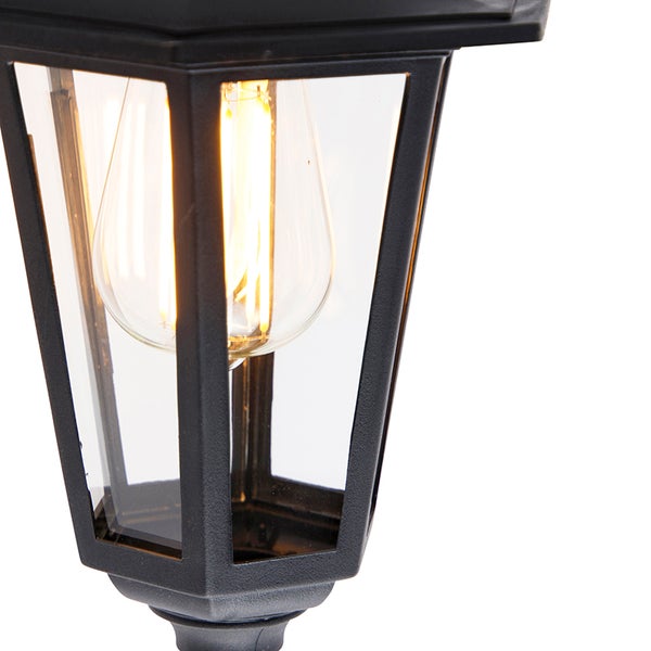 Schwarze Außenlaterne mit Glaseinsätzen und sichtbarem Leuchtmittel in Glühfadenoptik.