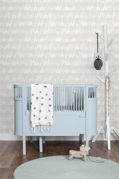 Helles Kinderzimmer mit blauem Kinderbett, gemusterter Tapete und Holzspielzeug