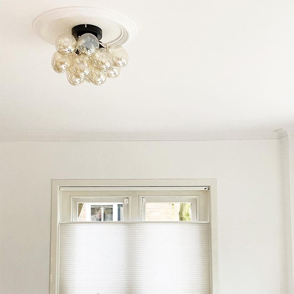 Deckenleuchte mit kugelförmigen Glaskörpern in einem hellen Raum mit Fenster