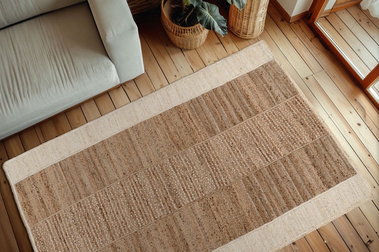 Wohnzimmer mit hellem Sofa und einem gewebten Jute Teppich in einem natürlich eingerichteten Raum mit großen Fenstern und Holzboden.