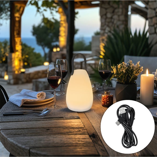 Tragbare LED-Außenleuchte mit Henkel und USB-Ladekabel auf einem hölzernen Gartentisch mit Weingläsern und Dekoration.