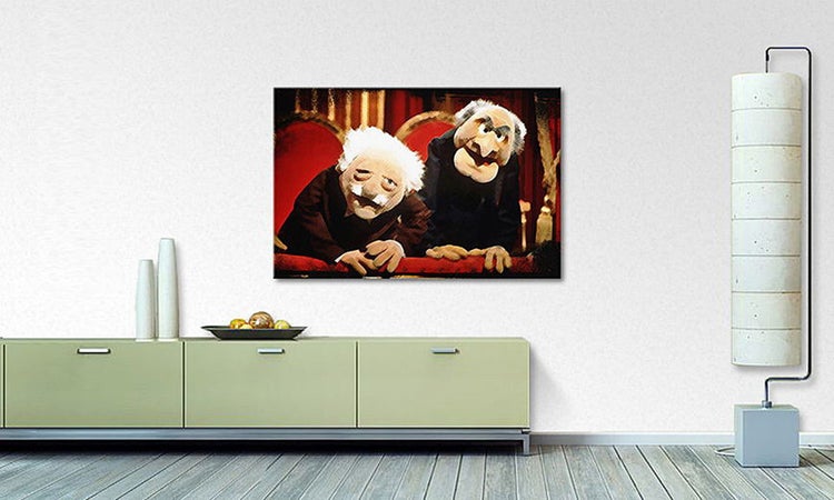 Modernes Wohnzimmer mit Muppets-Wandbild von Waldorf und Statler, einer Kommode und einer hohen Stehlampe.