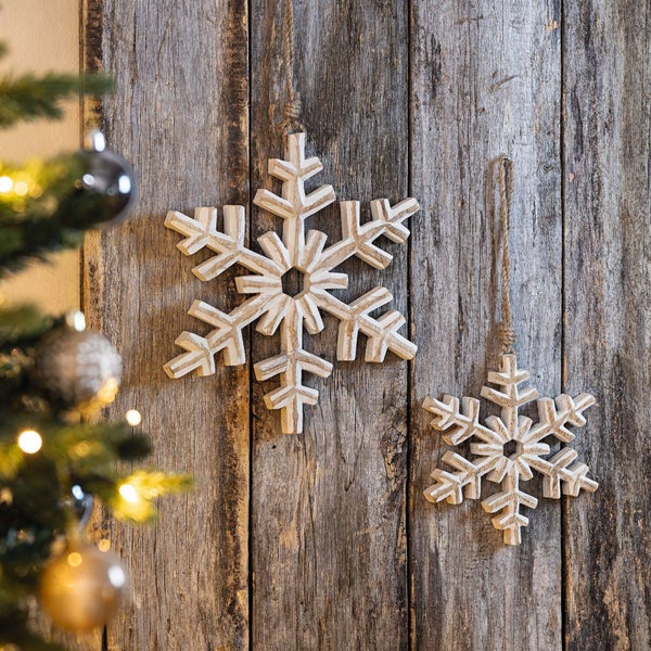 Dekorative Holzschneeflocken an einer Holzwand mit Weihnachtsbaum im Vordergrund
