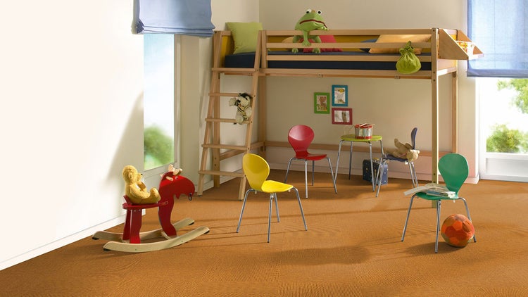 Hell eingerichtetes Kinderzimmer mit braunen Teppichfliesen in Rippenoptik, einem Hochbett aus Holz sowie bunten Stühlen und Spielzeug.