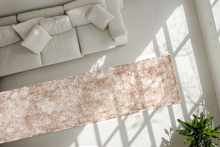 Draufsicht auf ein Wohnzimmer mit einem modernen Sofa und einem rechteckigen Teppich mit Vintage Muster vor einem hellen Boden.