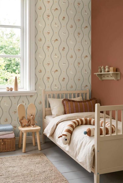 Kinderzimmer mit Vliestapete mit Zirkusmotiven, hellem Holzbett, Hasenstuhl und einer terracottafarbenen Wand.