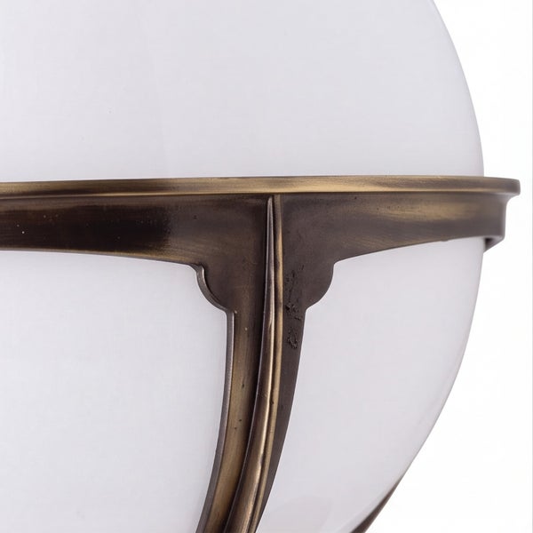 Detailansicht einer Leuchte mit weißer Glaskugel und antik-messingfarbenem Metallrahmen.