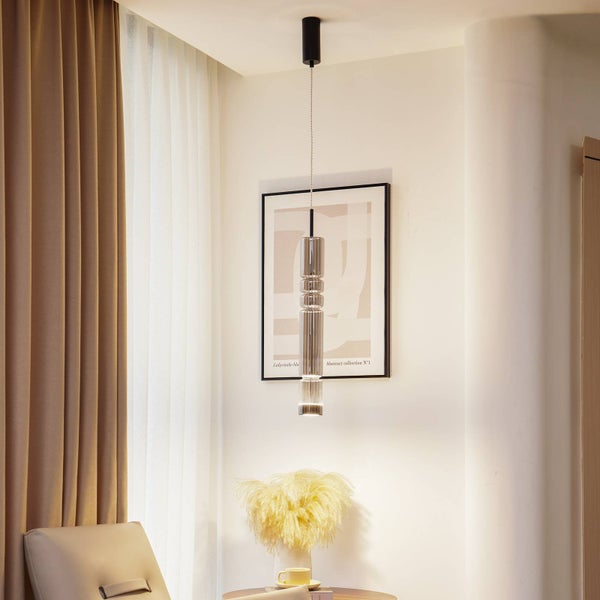 Moderne Pendelleuchte mit strukturiertem Glaszylinder in einem hellen Wohnraum mit Vorhängen und Wandbild.