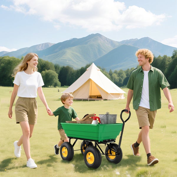 Familie mit grünem Gartenwagen auf einer Wiese vor einem Zelt und Bergen. Der Wagen hat gelbe Felgen und ist mit Gartenutensilien beladen.