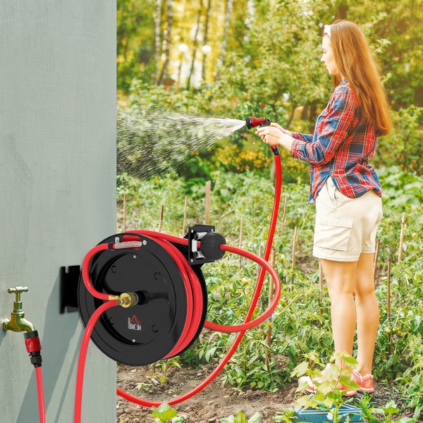 Frau bewässert Gartenpflanzen mit einem roten Gartenschlauch von einer schwarzen Wand-Schlauchtrommel mit Homcom Logo.