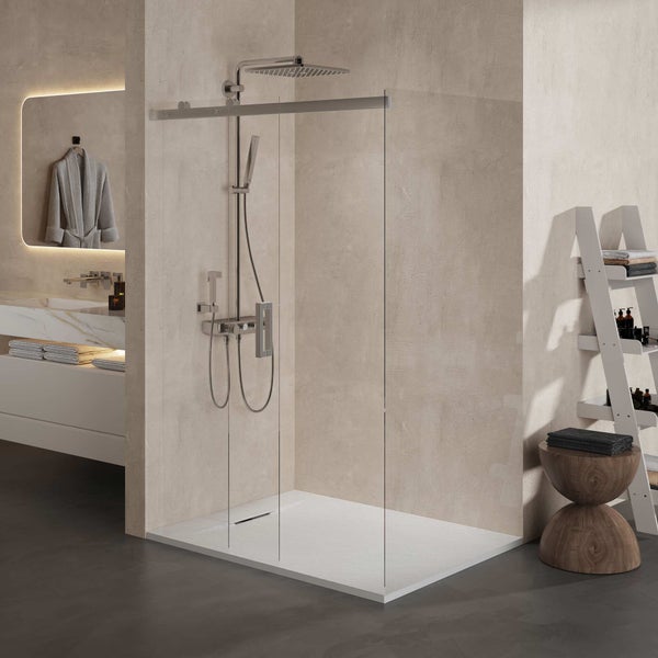 Moderne begehbare Dusche mit Glaswand, verchromtem Duschsystem, weißer Duschwanne und Wänden in Betonoptik in einem hellen Badezimmer.