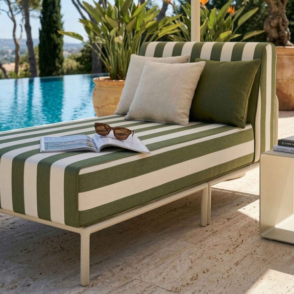 Modernes Outdoor-Daybed mit grün-weiß gestreiftem Muster und Zierkissen auf einer Terrasse neben einem Pool.