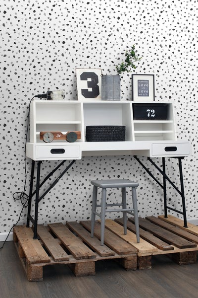 Schreibtisch mit Staufächern und Ablageflächen, kombiniert mit einem Hocker auf Holzpaletten.