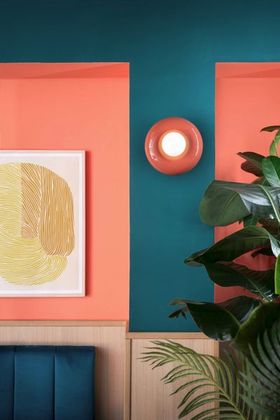 Dekoratives Interieur mit Wandleuchte, gerahmtem Bild und Zimmerpflanze.