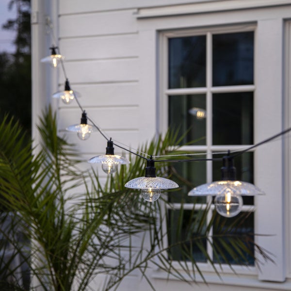 Solarstrahler beleuchtet Busch im Garten vor Haus