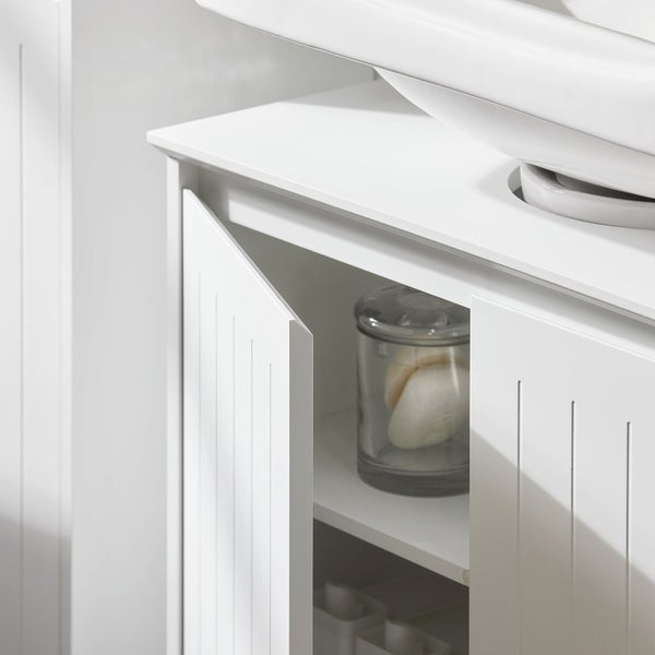 Detailansicht eines weißen Waschtischunterschranks mit geöffneter Tür und Badutensilien