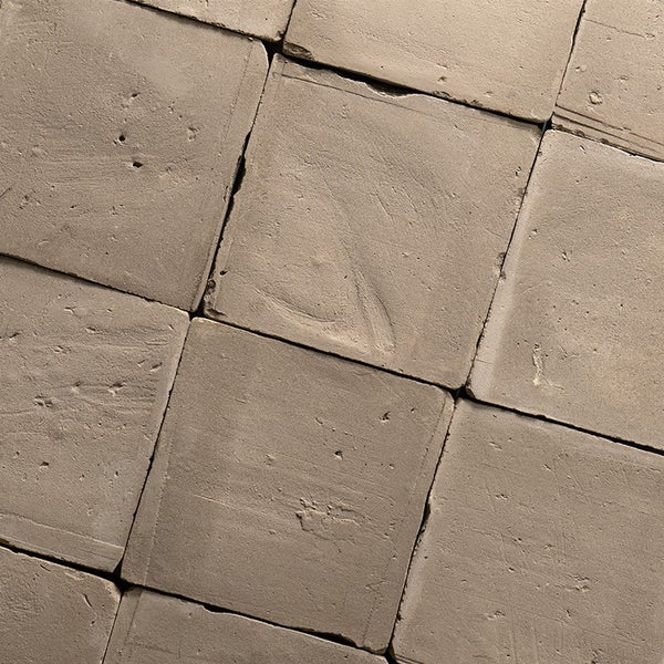 Quadratische Bodenfliesen aus Beton in rustikaler Optik mit unebener Oberfläche und strukturierter Haptik.