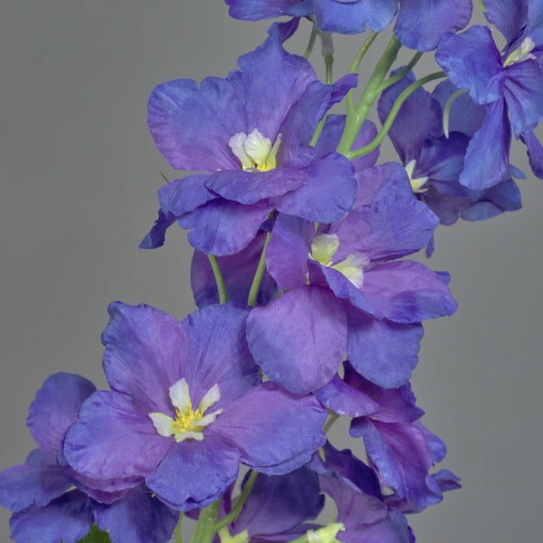 Künstlicher Rittersporn mit blauen Blüten und grünen Knospen an einem Stiel.