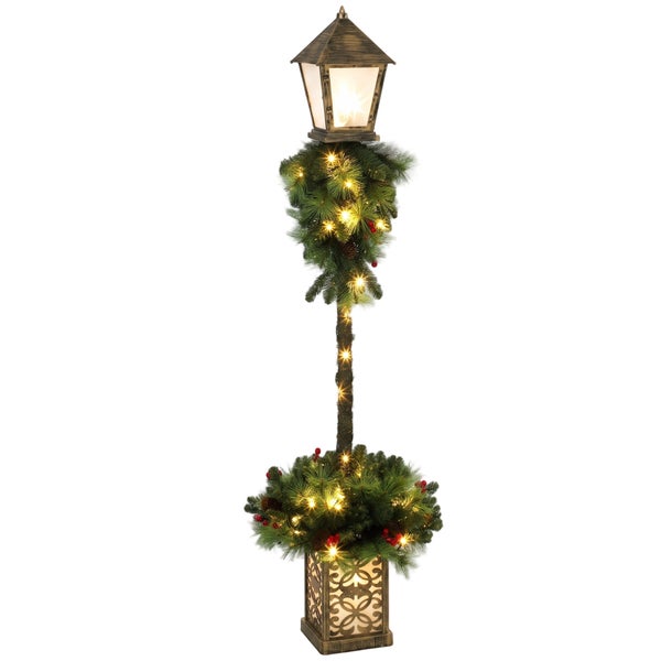 Beleuchtete Weihnachtsstraßenlaterne mit Tannengrün, Zapfen und Beeren als festliche Weihnachtsdekoration.
