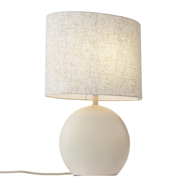 Moderne Tischleuchte mit rundem Keramikfuß und ovalem Textilschirm in hellbeiger Leinenoptik.