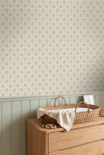 Helles Kinderzimmer mit floral gemusterter Vliestapete über Holzpaneelen und einem Wickelkorb auf einer Holzkommode.