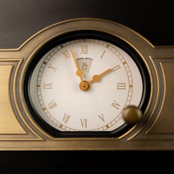 Analoge Wanduhr mit römischen Ziffern und messingfarbenem Rahmen im klassischen Design.