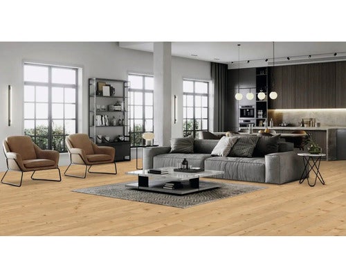 Heller Wohnraum mit Holzboden, Sofa, Sesseln und offener Küche.