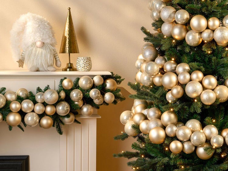 Weihnachtsdekoration mit dekoriertem Weihnachtsbaum und Kaminabschluss geschmückt mit glänzenden und matten Weihnachtskugeln im Wohnbereich