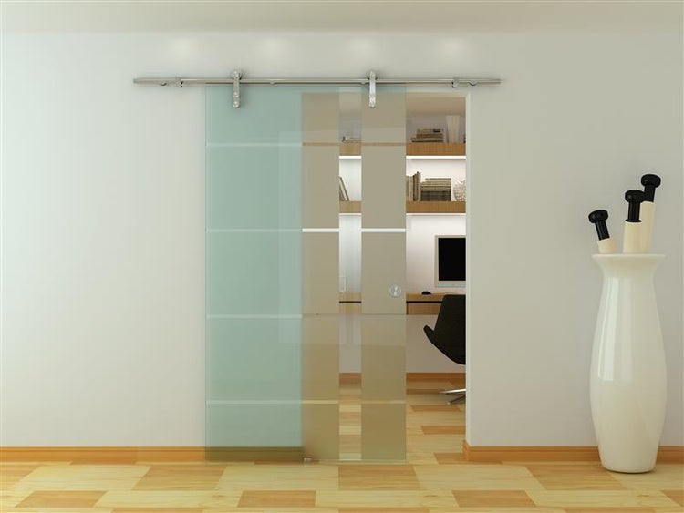 Moderne Schiebetür aus Glas mit Streifenmuster und sichtbarem Schienensystem aus Edelstahl vor einem hellen Arbeitszimmer.